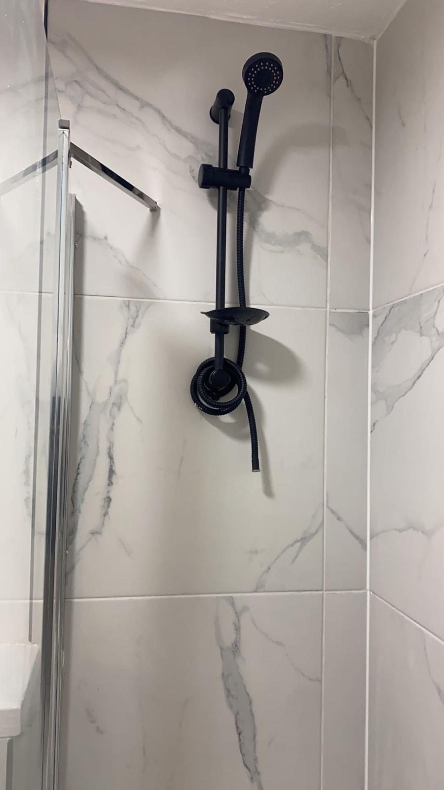 Matt black shower riser rail on marble-effect tiling